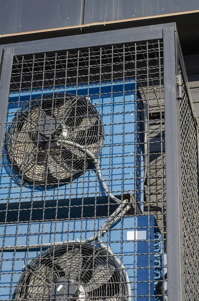 Health safety and the environment. Industrial ventilation system. Blue box type fans behind a metal anti-vandal grille.