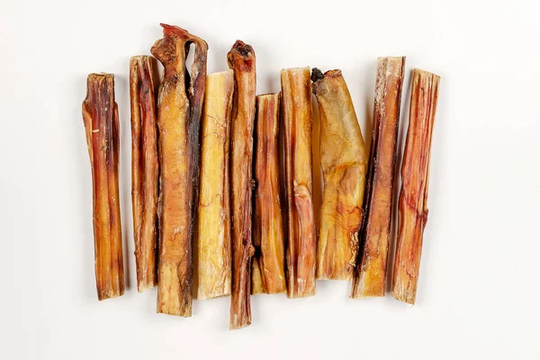 Helpful dried treats for pets. Dried bovine penis, bully sticks, beef pizzle on a white background. Mix of random treats of different lengths and diameters. Flat lay