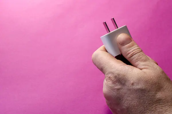 Die Hand Des Mannes Hält Einen Weißen Wandadapter Vor Rosa — Stockfoto