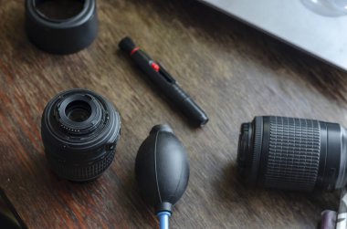 Fotografik lenslerin tozunu temizlemek. Lensler ve özel temizlik seti ahşap bir masada. İki lens, kaput, fırça, lastik armut.