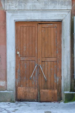 An old, sagging, closed wooden door. Tall door with stainless steel handles and doorbell. No people. clipart