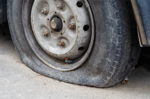 An old flat tire of an old rusty car. Side view. Selective focus.