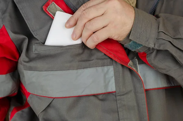 Göğüs cebinden beyaz bir akıllı telefonu çıkaran bir adamın yakın plan fotoğrafı. İş için özel kıyafetler giyen bir adam. Kırmızılı özel gri üniforma. Ön manzara. Seçici odak.