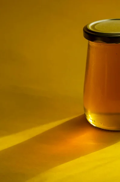 自然な砂糖代用品 健康的な食品の概念 黄色の背景にガラス瓶の中の生蜂の蜂蜜 液体有機蜂蜜のクローズアップ 選択的焦点 — ストック写真