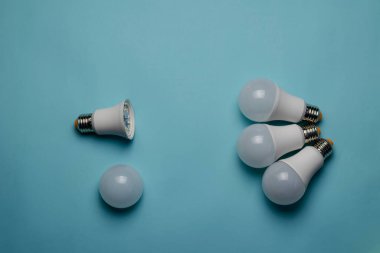 Mavi arka planda LED ışıkları olan yaratıcı minimalist kompozisyon. Üç yeni ampul difüzyonsuz bir ampule karşıdır. Düz Yat