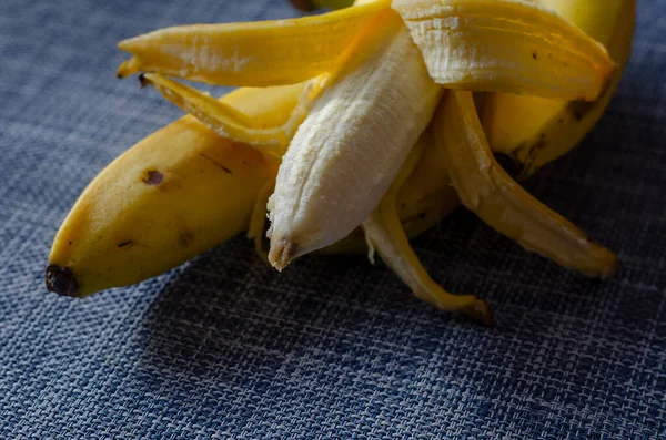 Три Неочищені Банани Поверх Яких Лежить Четвертий Частково Очищеною Шкіркою — стокове фото