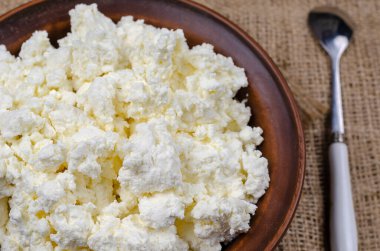 Kil bir kasede taze süzme peynir yakın plan. Bir kase kaymak ve çuvala bir kaşık. Yemek hazır. Sağlıklı yiyecekler. Seçici odak.