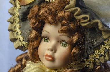 Eski model bir oyuncak bebeğin kafasının yakın çekimi. Yeşil gözlü sevimli gerçekçi oyuncak. Çiçekli ve dantelli oyuncak bebek elbisesi. Seçici odak.