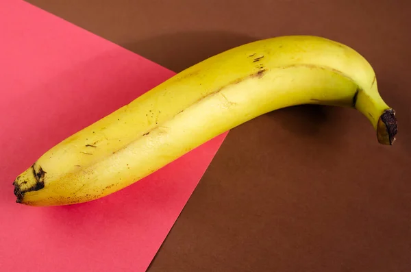 一个黄色香蕉的简约背景 成熟的香蕉皮在棕色和粉红色的背景 有选择的重点 — 图库照片
