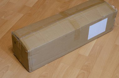 Posta hizmetleri konseptiyle alım satımı. Posta paketi kapalı dikdörtgen bir karton kutunun içinde yerde. Metin için kutunun üzerinde boş beyaz dikdörtgen.