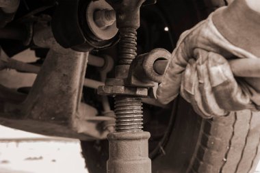 Lastik servisi, araba servisi konsepti. Eldivenle arabayı mekanik kriko ile kaldırıyor. Patlak bir lastiği değiştirmek. Seçici odak.