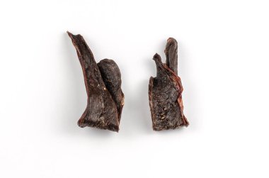 Beyaz arka planda evcil hayvan ödülleri. Kurutulmuş sığır kalbi. Köpekler için et cipsi. Yakın planda ince dilimler halinde kurutulmuş et..