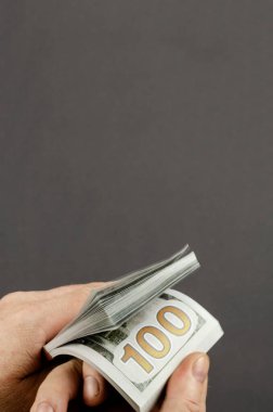 Bulanık, hareket bulanıklığı, yumuşak odaklanma. Bir adamın parmakları parayı sayar. 100 dolarlık banknotları tutan ellerin yakın çekimi. Boşluğu kopyala