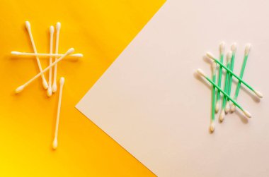 Beyaz ve sarı arka planda pamuk çubukları olan minimalist bir geçmişi var. Yukarıdan bir açıdan bak. Seçici odak.