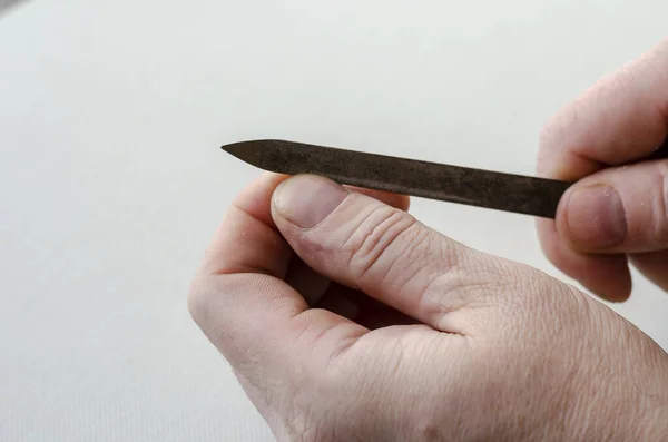 A man uses a nail file to trim his nails on his hand. His hands are on a white table. Close-up.  Selective focus.