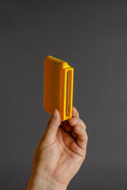 Gri arka planda 8 bitlik video oyunu kartuşu tutuyor. TV oyunları için sarı kartuşlar. Seçici odaklanma. Yakın plan..