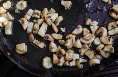 Çiğ mantarlar tavada kızartılır. Doğranmış mantarlar yağda kızartılır. Yemek, malzemeler. Seçici Odaklanma.
