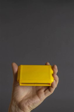 Gri arka planda 8 bitlik video oyunu kartuşu tutuyor. TV oyunları için sarı kartuşlar. Seçici odaklanma. Yakın plan..