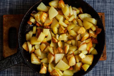 Tahta kesme tahtasının üzerinde kızarmış patates. Gelişigüzel dilimlenmiş patates. Yemek hazır. Düz yatıyordu