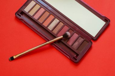 Makyaj, güzellik ve moda. Kadın kozmetik seti, göz farı ve göz kapağı. Kırmızı arka planda yeni bir kozmetik seti. Seçici odak.