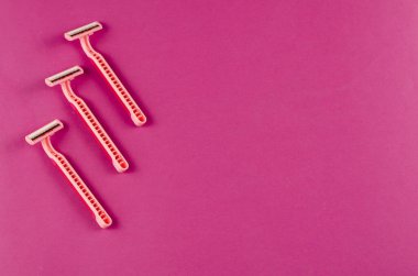 Pembe arka planda pembe plastik jiletler. Üç yeni kadın jileti. Seçici odaklanma. Boşluğu kopyala