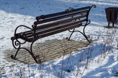 Winter City caddesinde boş, kahverengi bir bank. Tahta ve işlenmiş demir tezgah. Güneşli bir gün. Kimse yok..