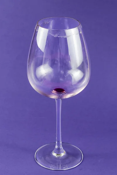 Empty dirty wine glass on a blue background. High stem red wine glass. Selective focus.