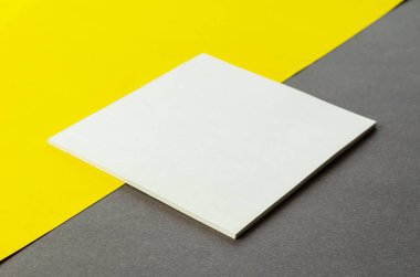 Sarı arkaplan üzerine beyaz kare boş yırtık not kağıdı. İki tonluk arka planda küçük bir deste kağıt çıkartması. Kimse yok..