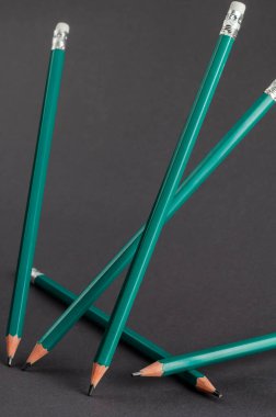 Gri arka planda duran yeşil kalemler. Bir grup yeni tahta kalem farklı açılarda rastgele yerleştirilmiş. Seçici odaklanma. İnsan yok. Odaklanma kavramı