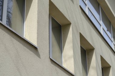 Pencereli sarı bir binanın ön cephesi. Cam ve betonun geometrik bileşimi. Dibe vurun. Seçici odak.