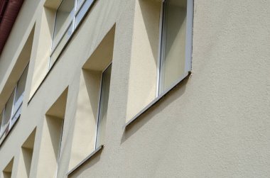 Pencereli sarı bir binanın ön cephesi. Cam ve betonun geometrik bileşimi. Dibe vurun. Seçici odak.