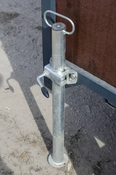 Trailer Stabilizing Jack Stand. The metal stand holds the car trailer in the parking lot. Daytime. Selective Focus.