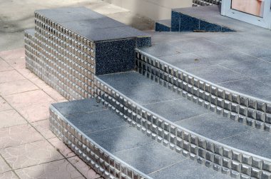 Engelliler için siyah basamaklar ve rampa. Seramik fayanslarla kaplı binaya giriş. Doğal ışık, gündüz. Seçici odak.