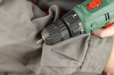 İş için gri kırmızı elbiseli bir adam elinde bir tornavida tutuyor. Yakın çekim, seçici odaklanma.