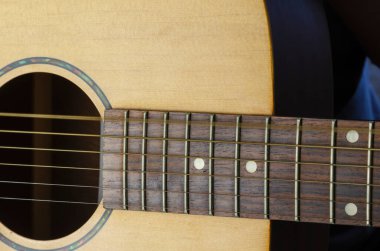 Akustik gitarda titreyen bir ip, hareket bulanıklığı. Sarı gitarın altıncı telinin titreşimi. İçeride. Yakın plan. Seçici odak.