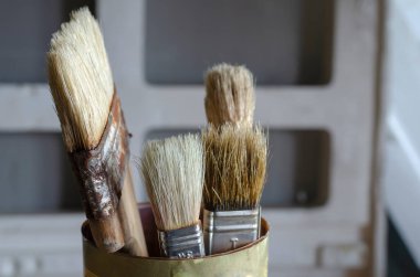 Ayakta duran eski boya fırçalarının yakın çekimi. Farklı genişlikte ve boyutlarda dört rastgele fırça. Odanın içinde. Yan görünüm.