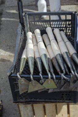 İçinde yeni metal bahçe aletleri olan bir tezgah. Siyah plastik kutularda ahşap saplı bahçe çapaları. Bahar Çiftçi Fuarı. Bahçe ve mahsul üretimi.