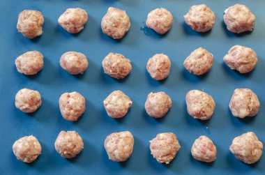 Çiğ şekilli köfteler, mavi üzerine güneş ışınları. Biberli, tuzlu ve baharatlı köfteler. Bir açıyla üstteki görünüm.