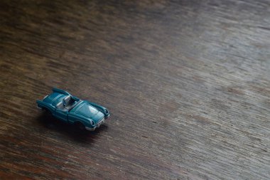 Çocukların hayali konsept oyunları. Küçük bir oyuncak araba kahverengi ahşap bir yüzey boyunca koşar. Yukarıdan bir açıdan bak. Seçici odak.
