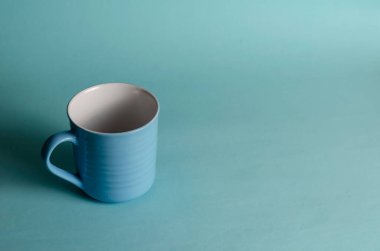 Açık mavi arkaplanda mavi bir fincanın minimalist kompozisyonu. Yeni boş seramik bardak. Yakın plan, seçici odaklanma. Boşluğu kopyala.