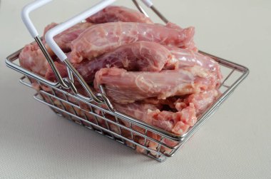 Hafif arka planda küçük bir alışveriş sepetinde çiğ tavuk boynu. Yakın plan tavuk sakatatı porsiyonu. Seçici odak.