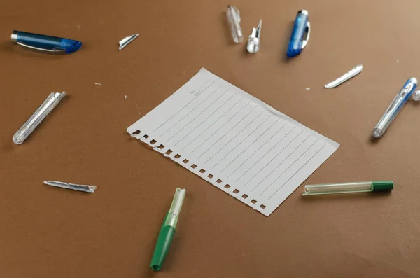 Törött Tollak Üres Papírlap Barna Asztalon Sok Véletlenszerű Műanyag Toll — Stock Fotó