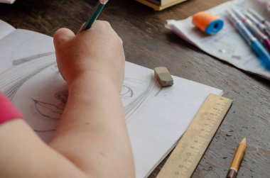 Yetişkin bir kadın kağıda kurşun kalemle bir resim çizer. Bir portre oluşturma, resim yapmayı öğrenme süreci. Bir açıdan yan görüş. Sanat, aktif eğlence. İnsan yok. Kapalı.