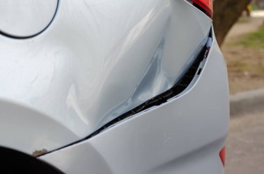 Trafik kazası oldu. Hasarlı arka çamurluğa ve gri bir sedanın tamponuna yakından bakın. Tampon parçaları kopmuş ve araba gövdesinde göçükler var. Aracın sol arka tarafında. Otomatik Sigorta