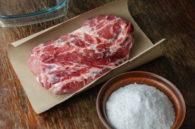 Ev yapımı Capicola (coppa). Kurutulmuş domuz filetosu adım adım tarifi. Kağıt üzerinde koca bir parça çiğ domuz eti. Tuzlu kil kasesi. Et turşusu için hazırlık. Geleneksel İtalyan mutfağı.