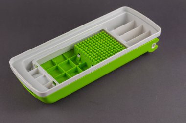 Gri arka planda manuel sebze kesicisi. Sebze, meyve, yumurta, peynir ve etten oluşan mutfak helikopteri için beyaz-yeşil plastik kaplama. Mutfak aletleri.