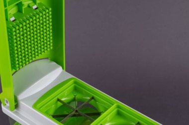 Gri arka planda manuel sebze kesicisi. Şeffaf bir konteynırda özel bıçak ve eklentiler. Mutfak aletleri.