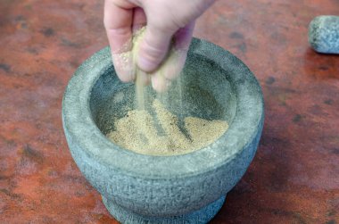 Bulanık hareket, bulanıklık. Adam gri taştan havan mermisi ve baharat kalitesini kontrol ediyor. Marjoram, biber, fesleğen, biberiye, hardal, böğürtlen karışımını granit bir harca döküyor.