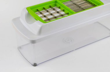 Beyaz arka planda manuel sebze kesicisi. Şeffaf bir konteynırda özel bıçak ve eklentiler. Mutfak aletleri.