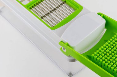 Beyaz arka planda manuel sebze kesicisi. Şeffaf bir konteynırda özel bıçak ve eklentiler. Mutfak aletleri.